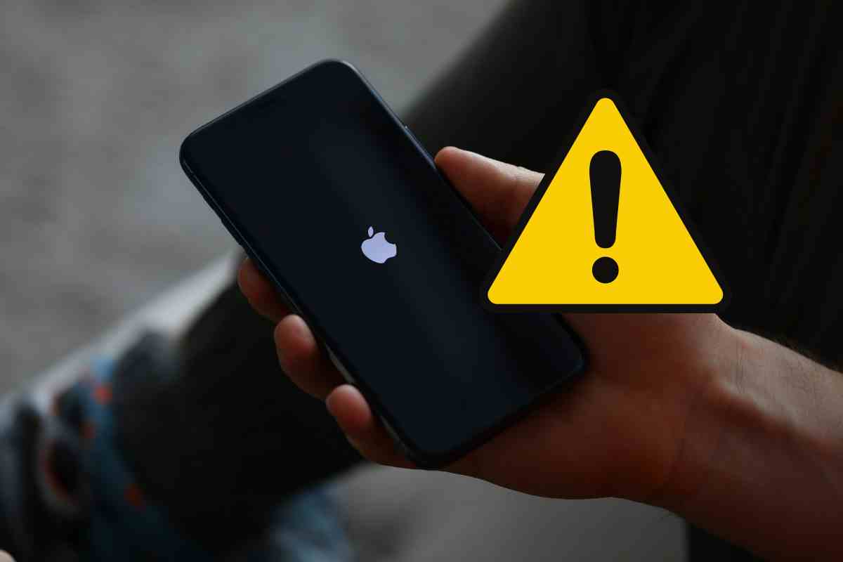 mano che regge un iphone e segnale di pericolo