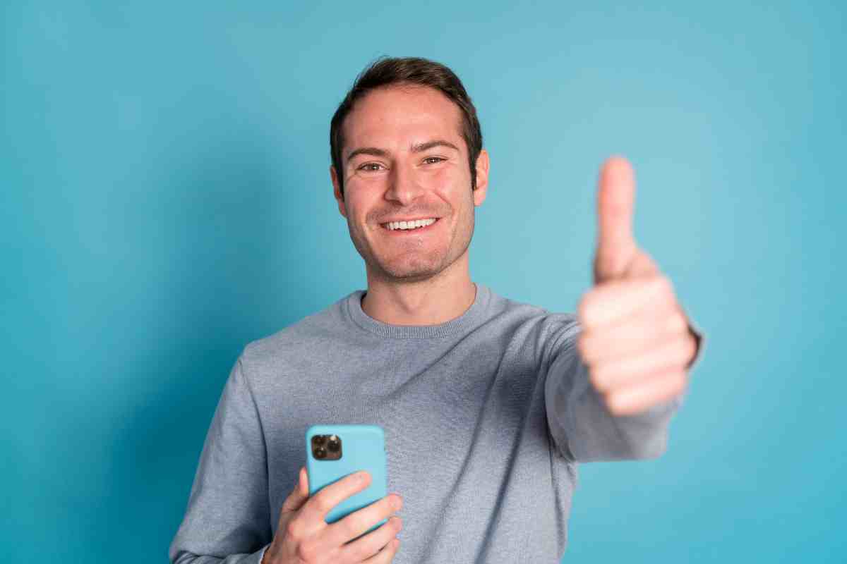 uomo con smartphone che fa segno ok