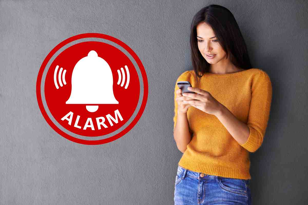 donna con smartphone e allarme