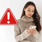 donna con telefono e segnale di pericolo