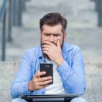 uomo guarda telefono sconvolto